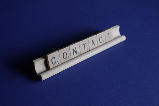 Scrabble tiles in a holder, spelling "contact"